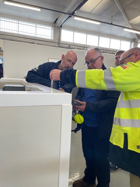 Standing around the entrance to PASS' mock substations, Phil and two attendees take a reading using the EA Technology UltraTEV Plus 2.