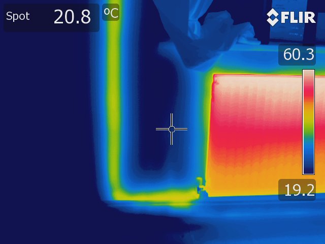 Thermal image of a pipe in a wall feeding a radiator. The image is taken using a Rainbow colour palette. 