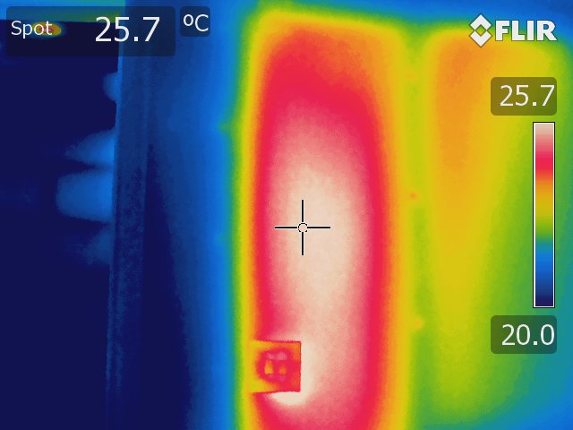 Thermal image of a wall with a radiator fitted to the opposite side taken using a Rainbow palette. A large red and white area indicates the radiator is functioning correctly. 