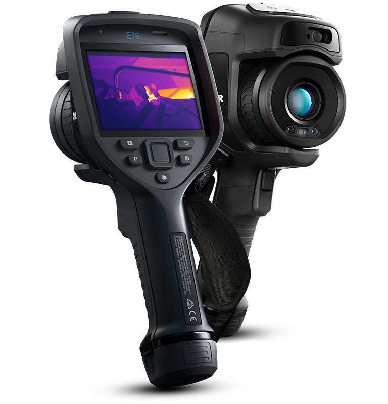 Two FLIR E76 Thermal Cameras. The camera in the foreground is slightly angled and facing backwards, on its display there is a thermal image of pipes. The camera in the background is also angled but facing forwards. 