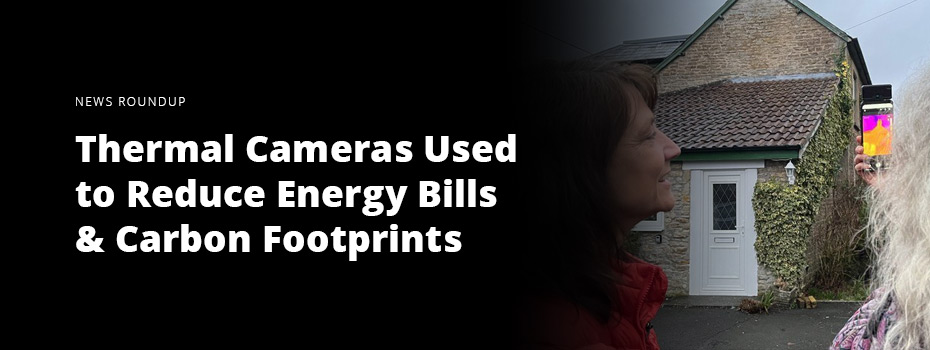 On the left, white text on a black background reads 'News Roundup: Thermal Cameras Used to Reduce Energy Bills & Carbon Footprints.' On the right two women use a smartphone with a thermal imaging attachment to inspect a stone house with a white door and climbing plant along one wall. 