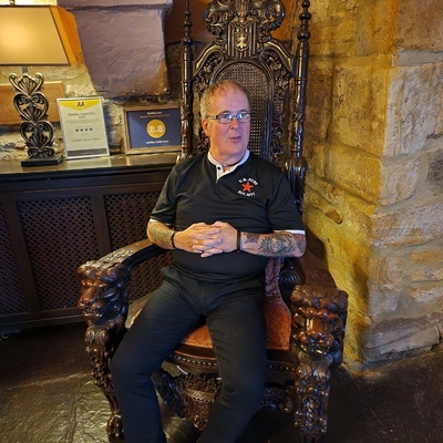 Paul sits in a wooden throne. 