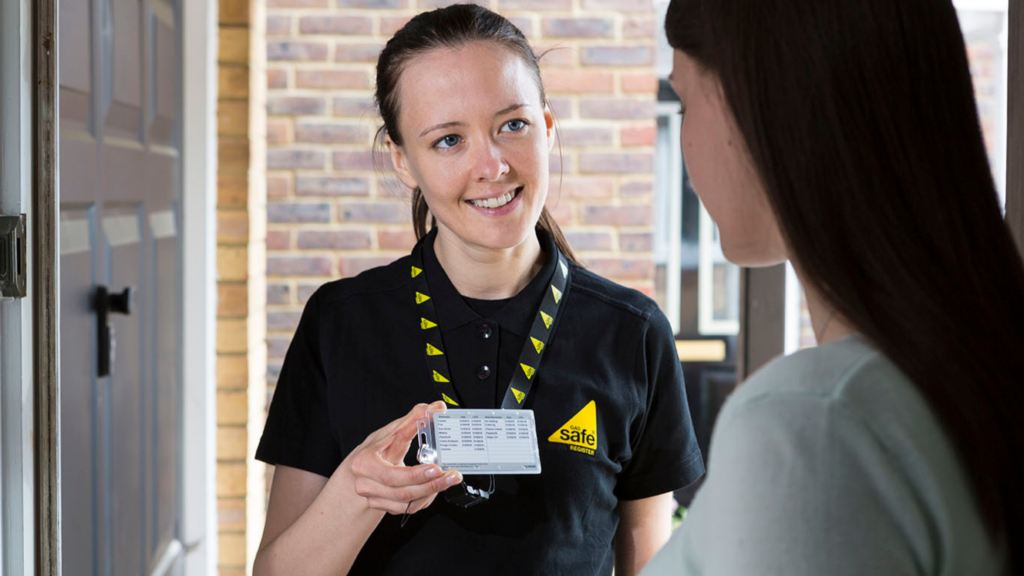 A Gas Safe registered engineer shows her Gas Safe ID badge to the female homeowner/tenant.
