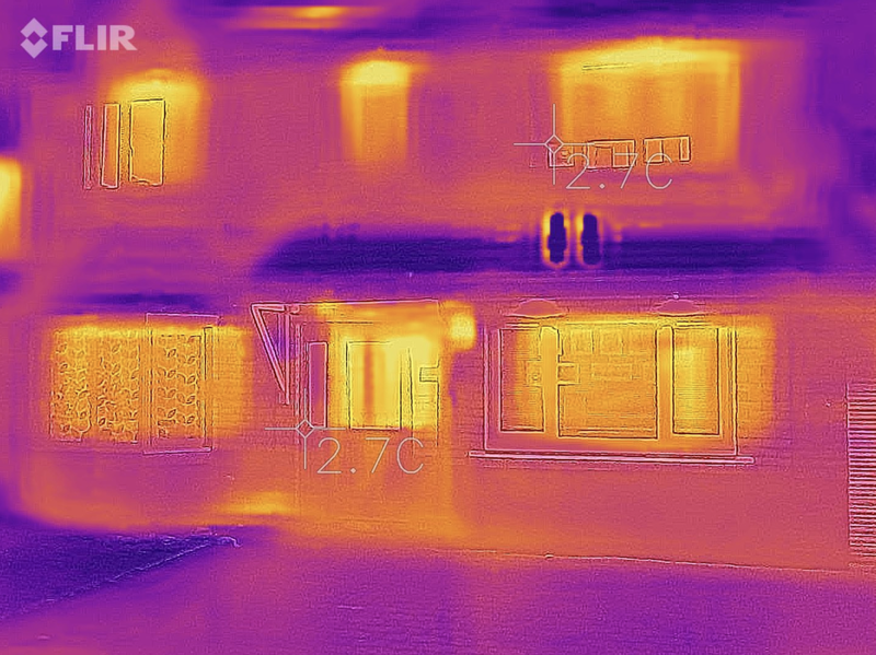 Thermal image of an energy efficient home. The house is purple and blue with the only instances of yellow spots coming from the windows.