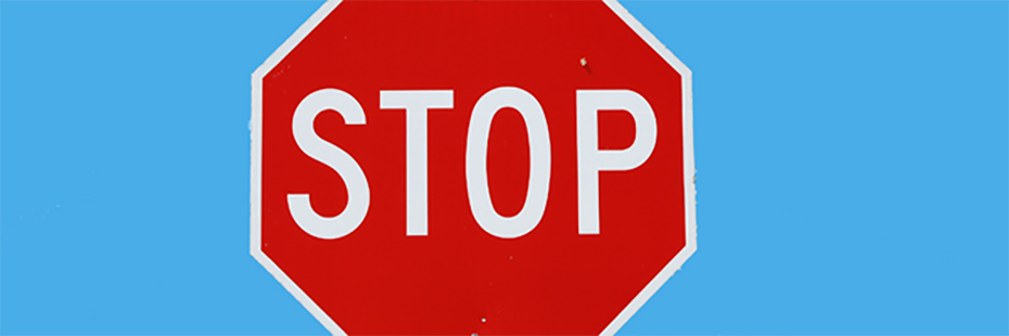 A red, road, stop sign is in the centre of a light blue background. 