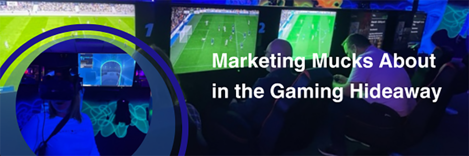 To the right of the image large white text reads "Marketing Mucks About in the Gaming Hideaway". It sits on a photo background of three men sitting in a row with their backs to the camera playing FIFA on flat screen TVs in a dark room illuminated by neon light and decorated with fluorescent paint. In the bottom left of the image is a circular photo of a young woman with shoulder-length hair, wearing a VR headset and behind. She is standing in the same dark room as the men. The selfie is framed by a dark blue circular border. 