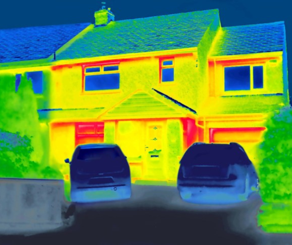 A Thermal image of house and two cars. The image uses a rainbow thermal palette. Most of the house is bright yellow with red rims around the windows and doors. The ceiling is a blue-green while the cars are a dark blue.