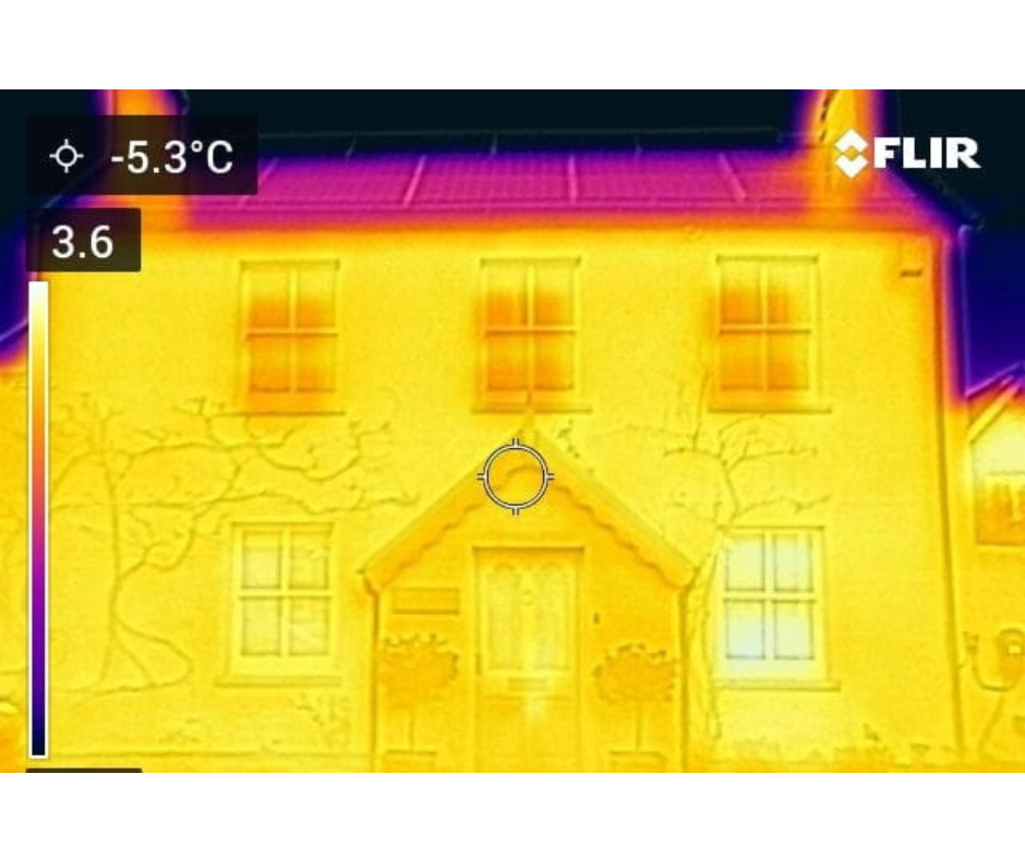 Thermal image of a house topped with solar panels. The house is bright yellow while the solar panel roof is pink-purple. 