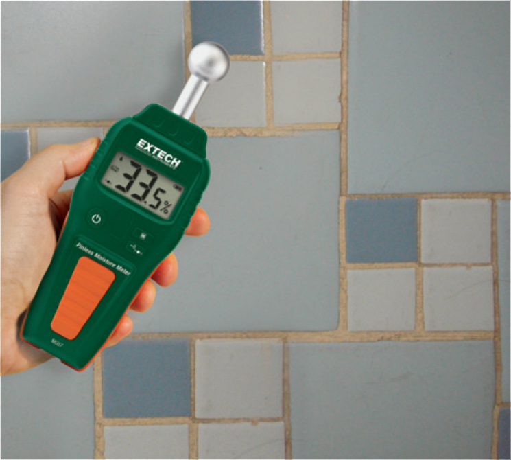 The Extech MO57 Pinless Moisture Meter in action, the operator is checking a bathroom wall for moisture levels and the reading shows 33.5%.