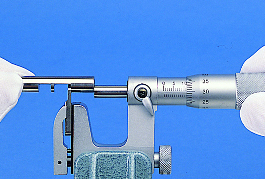 Mitutoyo Series 117 Uni-Mike Interchangeable Anvil Micrometers measuring an instrument.