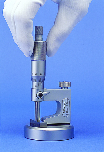 Mitutoyo Series 317 Uni-Mike Interchangeable Anvil Micrometers measuring an instrument.