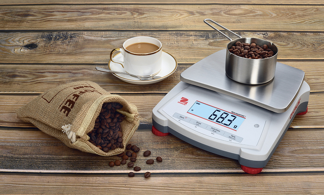 Ohaus Navigator NV Precision Portable Balance weighing some coffee beans.