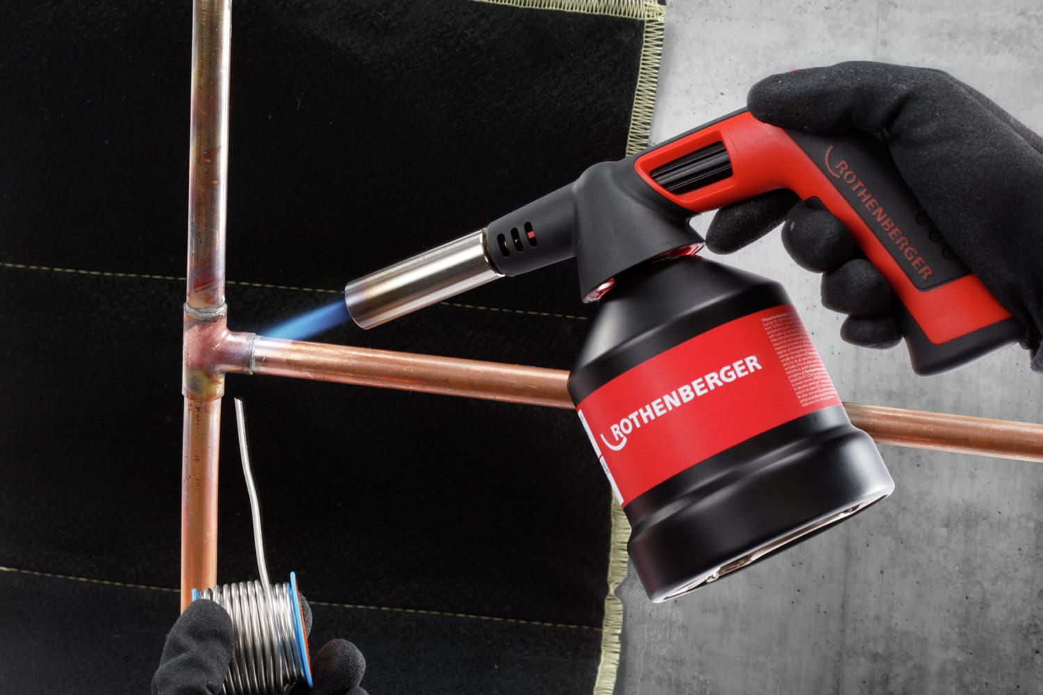 The Rothenberger 1000002358 Roflame 4 Piezo Soft Soldering Torch heating a pipe.